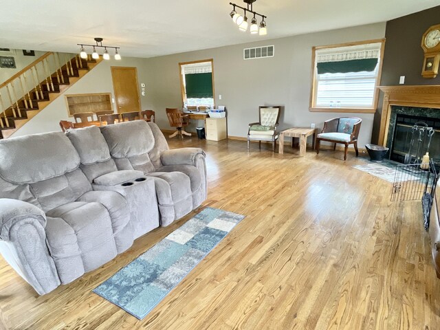 living room featuring wood finished floors, stairs, a high end fireplace, rail lighting, and visible vents