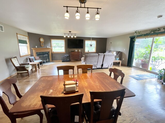 dining area with rail lighting, visible vents, light wood-style floors, baseboards, and a fireplace