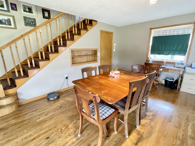 dining space with wood finished floors and stairs