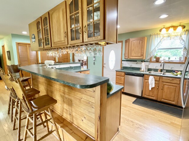 kitchen with a sink, dark countertops, recessed lighting, dishwasher, and a breakfast bar