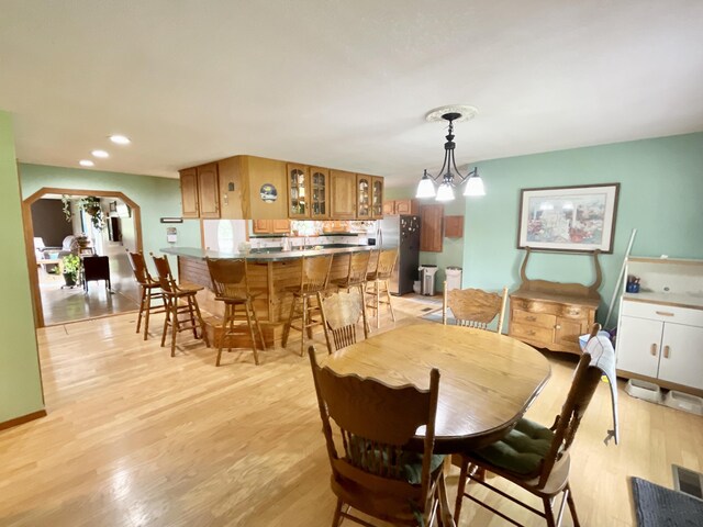 dining room featuring recessed lighting, arched walkways, light wood-style floors, and an inviting chandelier