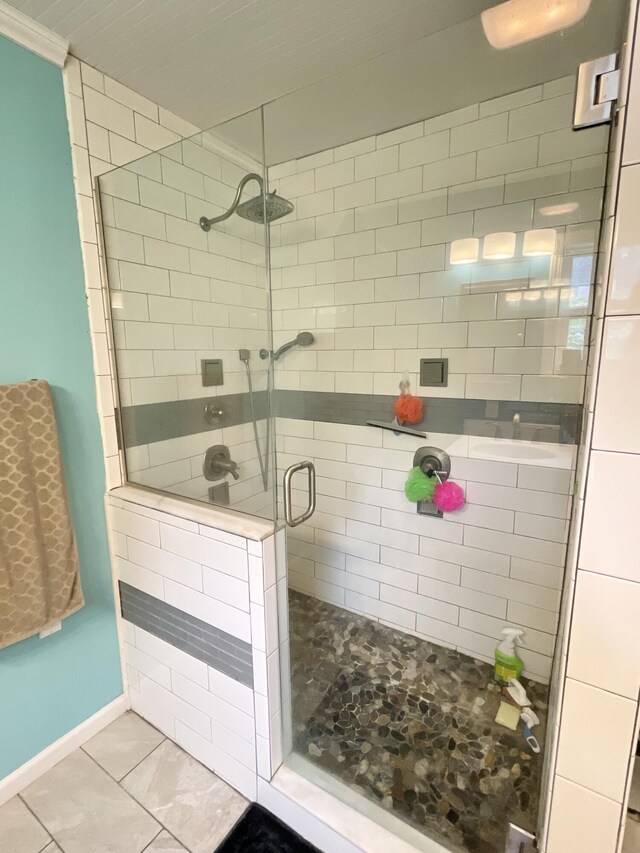 bathroom featuring baseboards, tile patterned floors, and a stall shower