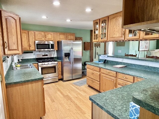 kitchen featuring dark countertops, light wood-style flooring, appliances with stainless steel finishes, and a sink