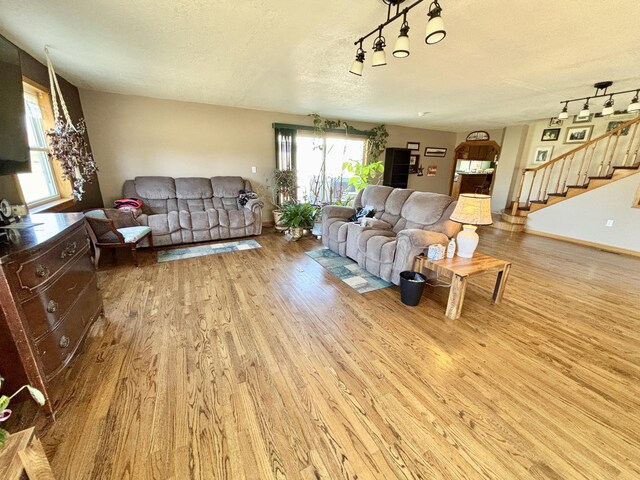 living area with stairs, a healthy amount of sunlight, wood finished floors, and a textured ceiling
