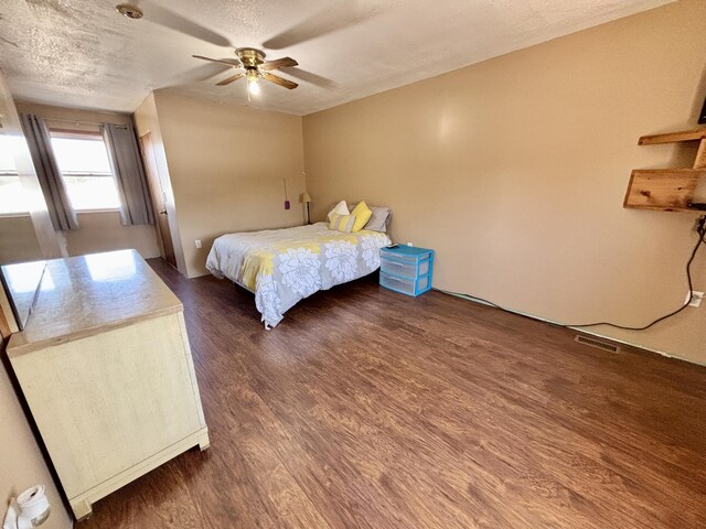bedroom with ceiling fan, dark wood-style flooring, a textured ceiling, and visible vents