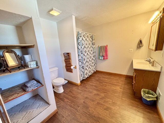 bathroom with wood finished floors, visible vents, toilet, baseboards, and a textured ceiling
