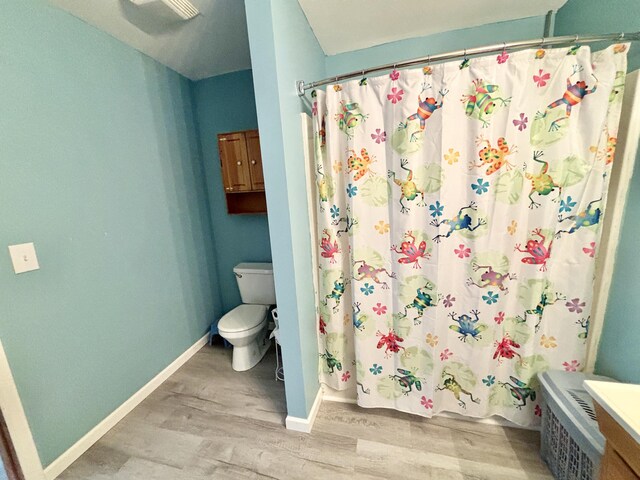 full bath with baseboards, wood finished floors, and toilet