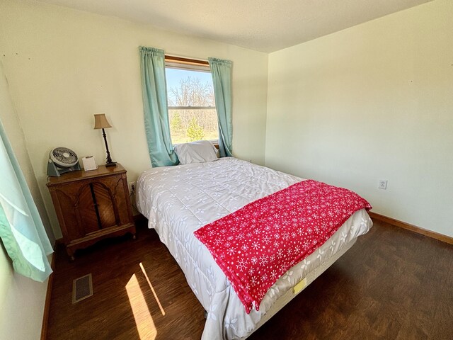 bedroom featuring wood finished floors, visible vents, and baseboards