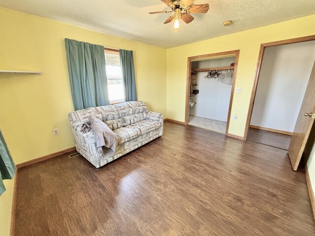 living area with baseboards, a ceiling fan, wood finished floors, and a textured ceiling