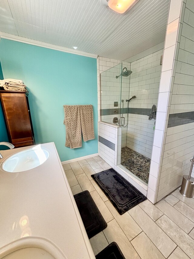full bathroom featuring a sink, a shower stall, and crown molding