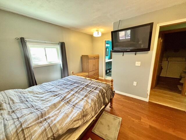 bedroom with wood finished floors, a textured ceiling, and baseboards