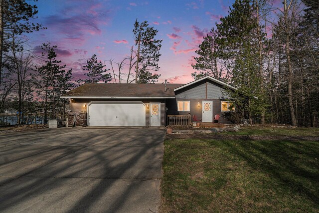 view of front facade with an attached garage, a yard, and driveway