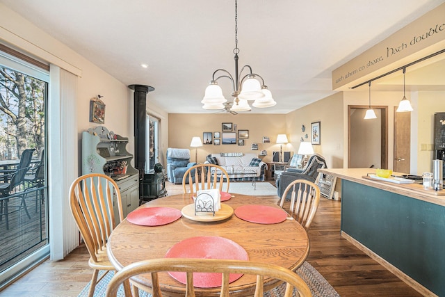 dining space featuring light wood-type flooring, a wood stove, and an inviting chandelier