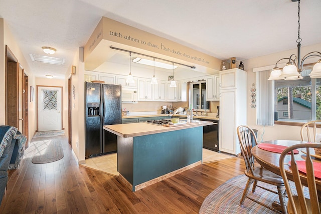 kitchen featuring a kitchen island, visible vents, light wood-type flooring, light countertops, and black appliances