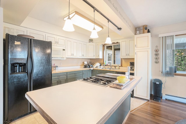 kitchen with black refrigerator with ice dispenser, stainless steel gas cooktop, a baseboard radiator, light countertops, and a sink