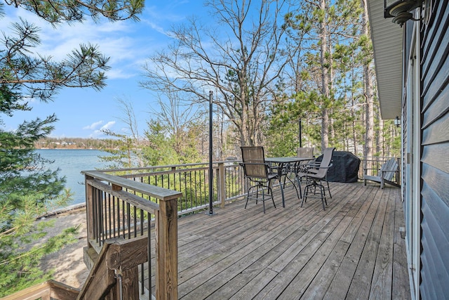 deck with a water view and outdoor dining space