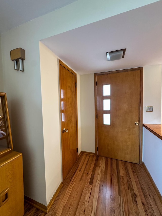 doorway featuring baseboards and wood finished floors