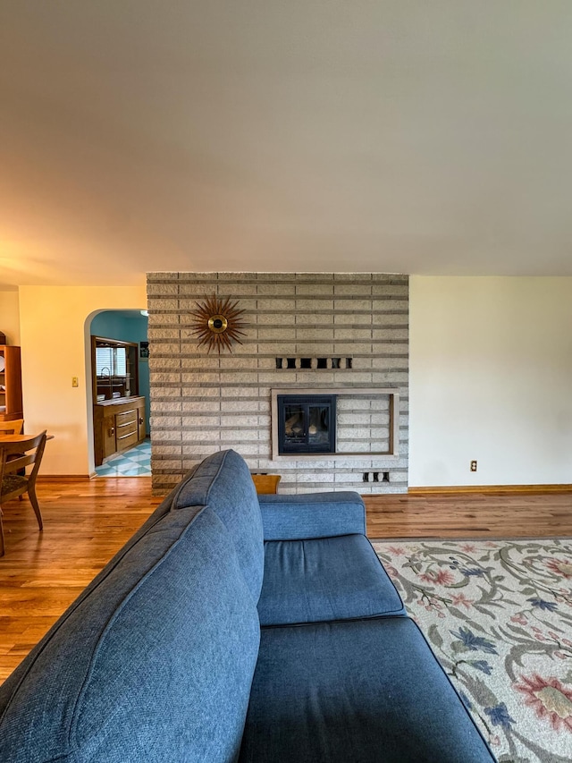 living area with baseboards, arched walkways, and wood finished floors