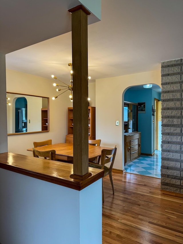 kitchen featuring stainless steel fridge, arched walkways, baseboards, and wood finished floors