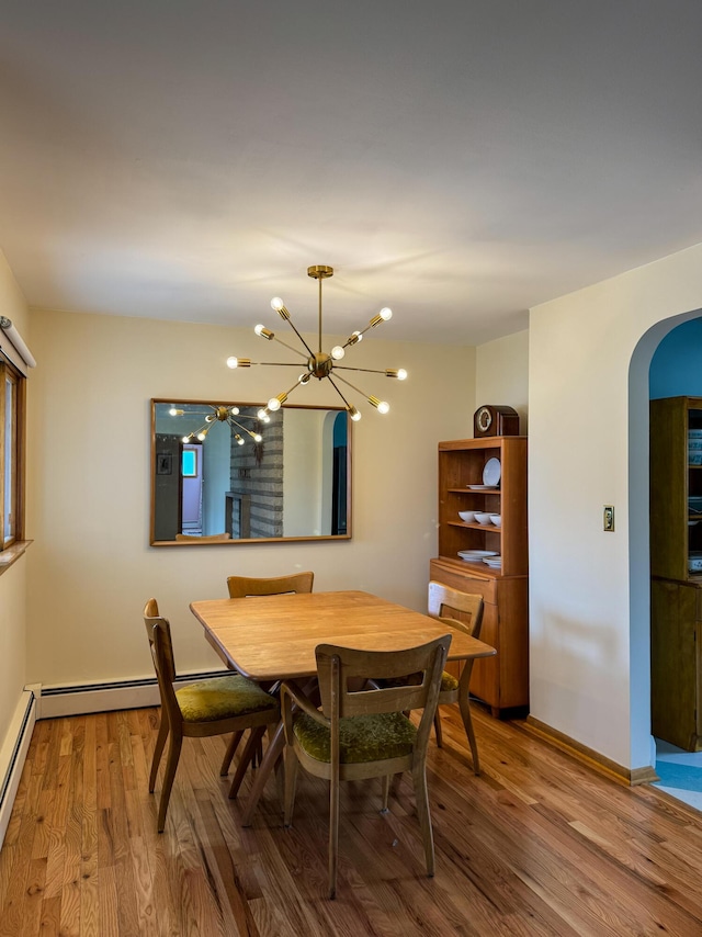 dining space featuring arched walkways, baseboards, a chandelier, and wood finished floors