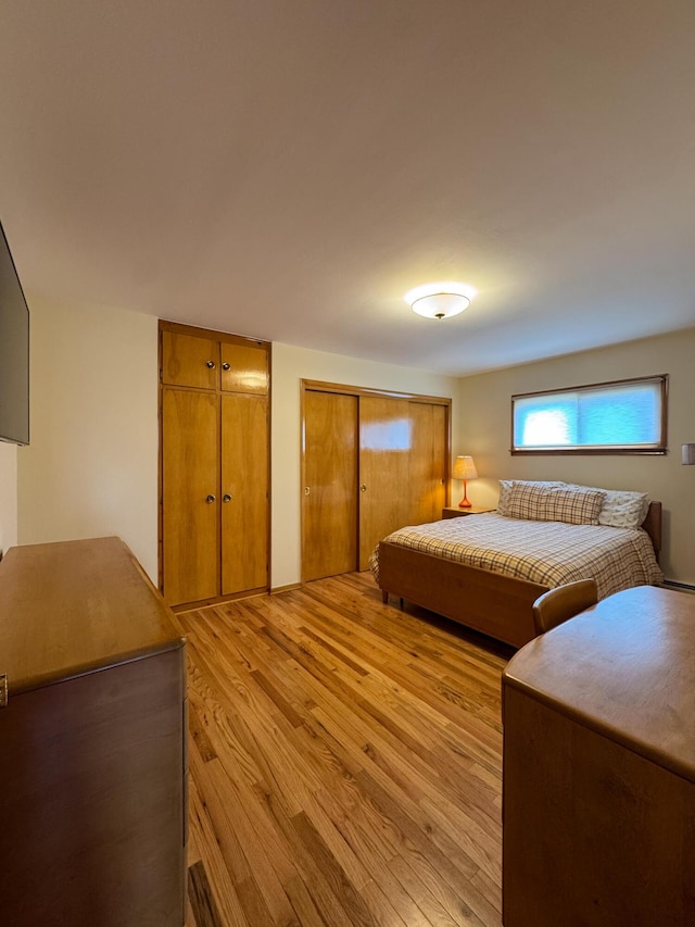 bedroom with light wood-style floors and multiple closets