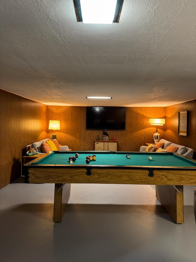 game room featuring wooden walls, a textured ceiling, and pool table