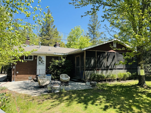 17745 Shubert Hwy, Alpena, MI 49707 - back of property featuring a patio area, a lawn, brick siding, a sunroom, and a chimney