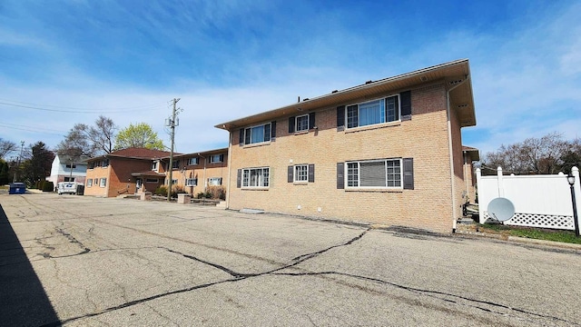 rear view of house with fence and brick siding