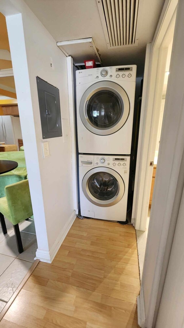 clothes washing area with laundry area, light wood-style flooring, stacked washer / dryer, electric panel, and visible vents