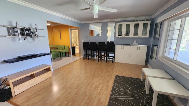 living room with wood finished floors, ceiling fan, crown molding, and a healthy amount of sunlight
