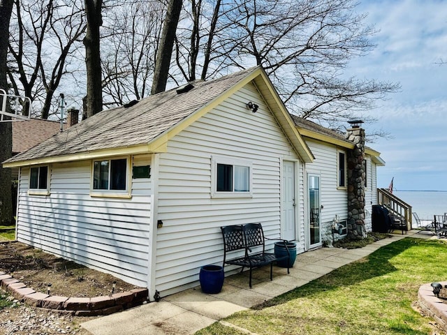 1106 Houghton View Dr, Houghton Lake, MI 48629 - view of home's exterior featuring a chimney, roof with shingles, and a yard