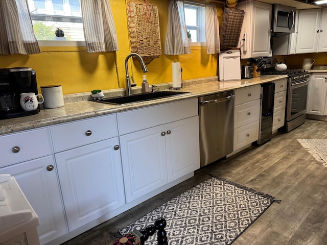 1106 Houghton View Dr, Houghton Lake, MI 48629 - kitchen with stainless steel appliances, a sink, white cabinetry, and wood finished floors