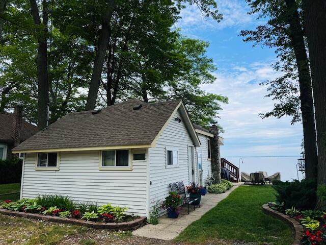 1106 Houghton View Dr, Houghton Lake, MI 48629 - view of side of home with a lawn and roof with shingles