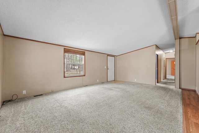 unfurnished room featuring carpet floors, a textured ceiling, visible vents, and lofted ceiling