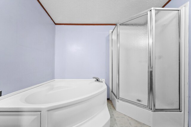 bathroom with a garden tub, a shower stall, and a textured ceiling