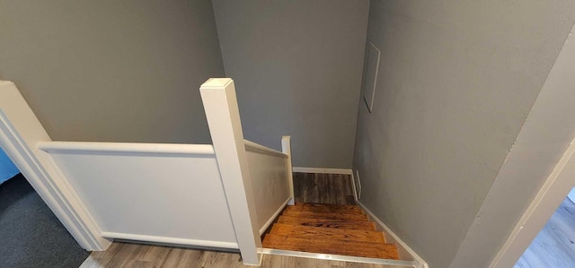 staircase featuring wood finished floors and baseboards