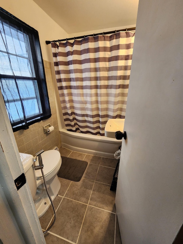 full bath featuring tile patterned floors, shower / tub combo with curtain, toilet, and tile walls