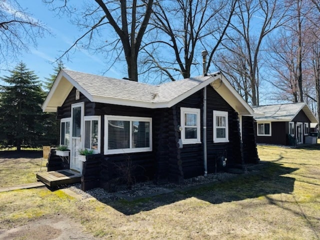 view of side of property with a yard and log siding