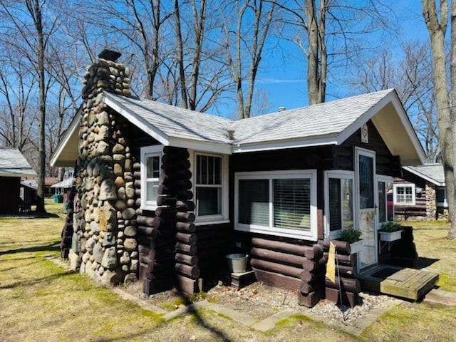 view of home's exterior featuring a chimney, a yard, and log exterior