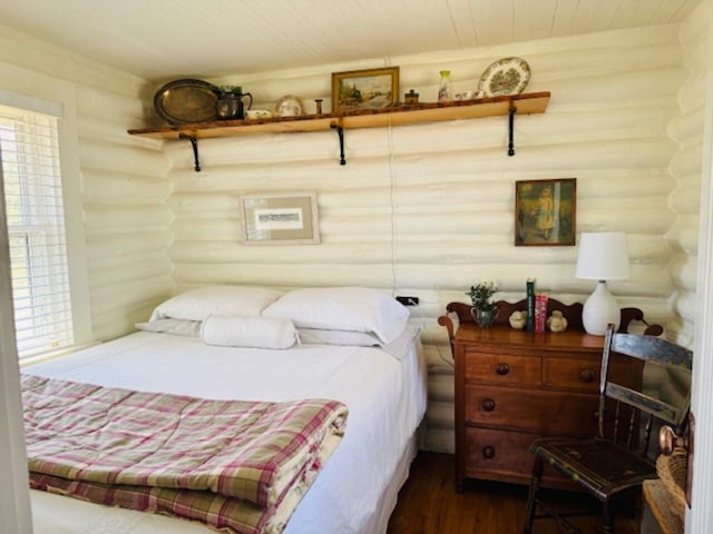bedroom with dark wood finished floors, log walls, and wood ceiling