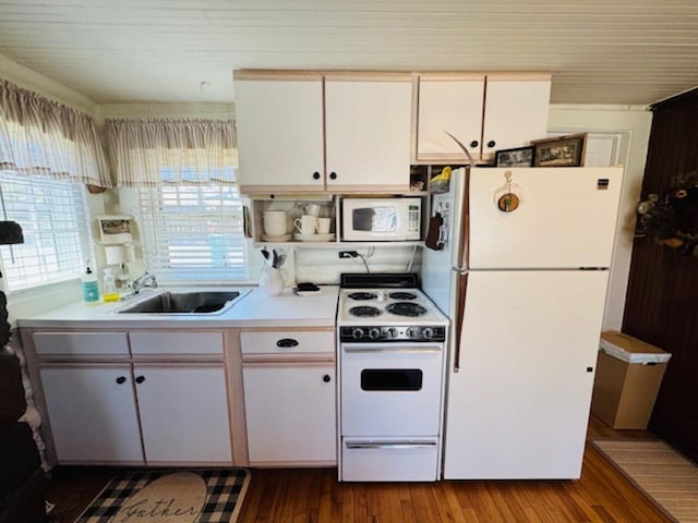 kitchen with wood finished floors, white appliances, light countertops, a sink, and white cabinetry