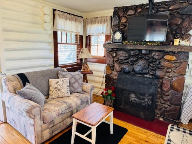 living area featuring hardwood / wood-style flooring and a stone fireplace