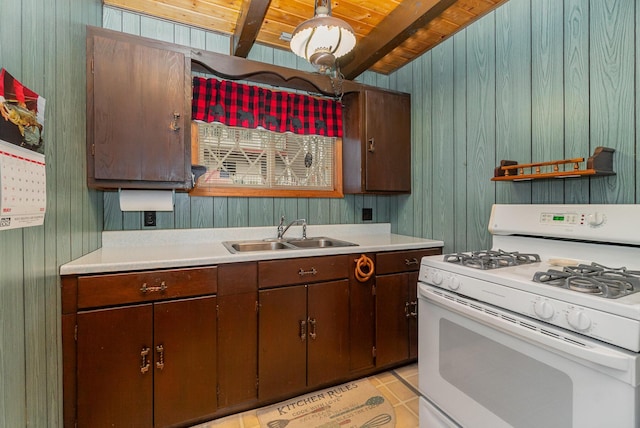 kitchen featuring beam ceiling, a sink, light countertops, white range with gas cooktop, and wood ceiling