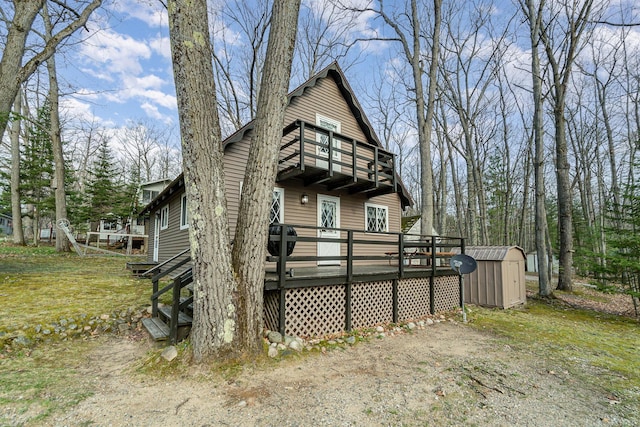 back of property featuring an outdoor structure, a balcony, a storage shed, and a deck