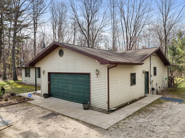 321 Greenleaf Dr, Houghton Lake, MI 48629 - view of side of property featuring a garage, a shingled roof, and driveway