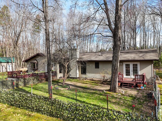 321 Greenleaf Dr, Houghton Lake, MI 48629 - rear view of house with french doors, a chimney, a lawn, and a deck