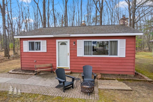 2931 Boulan Dr, Lewiston, MI 49756 - view of front of house with a chimney, a fire pit, and a patio area