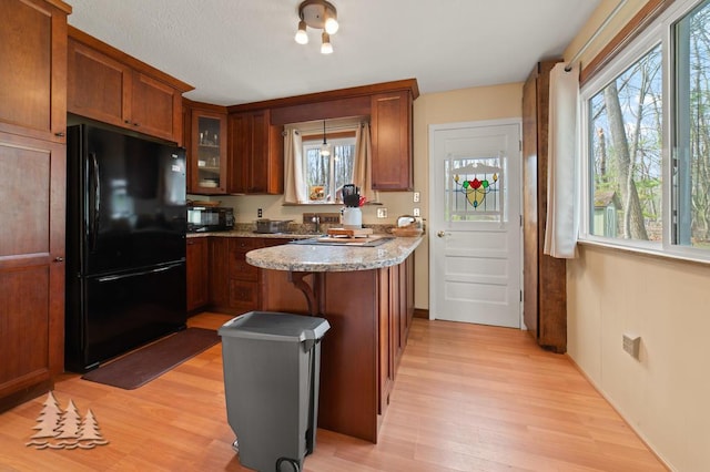 2931 Boulan Dr, Lewiston, MI 49756 - kitchen featuring a center island, light wood finished floors, black appliances, and glass insert cabinets