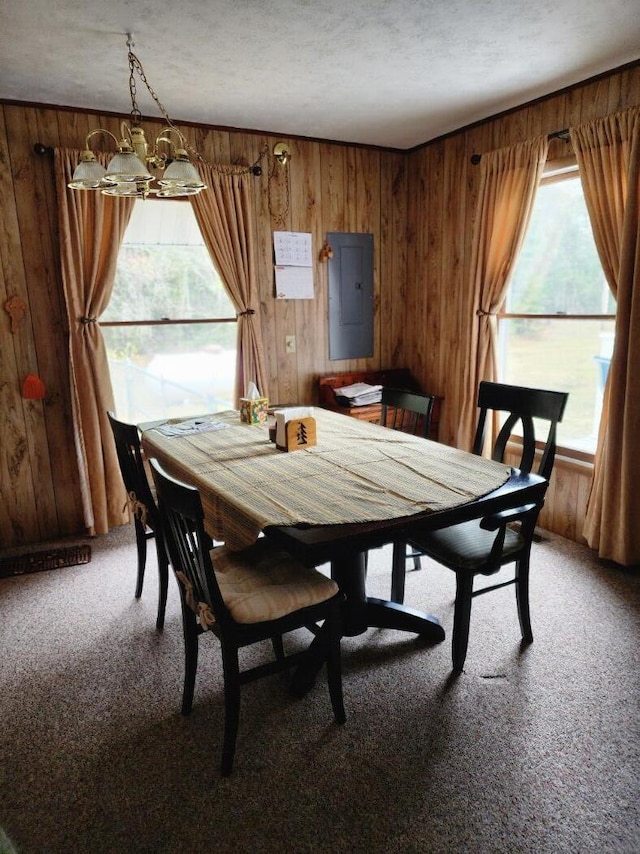 dining area with electric panel, a textured ceiling, an inviting chandelier, light carpet, and wooden walls