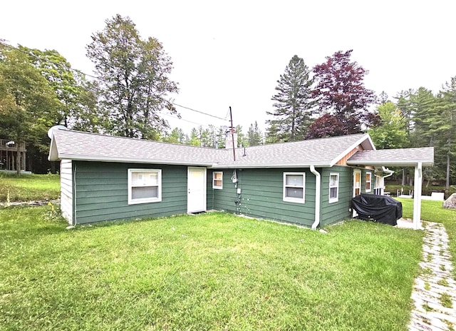 rear view of property with a yard and a shingled roof